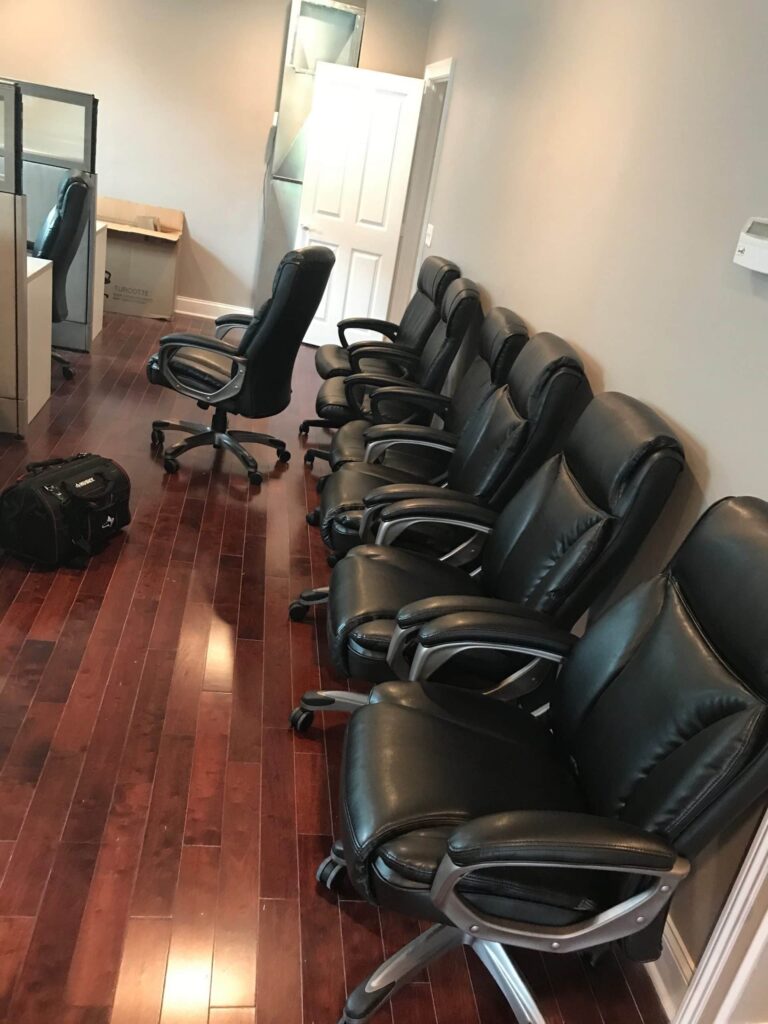 Row of black leather office chairs in a modern workspace.