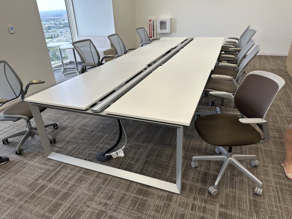 Modern office conference room with ergonomic chairs and adjustable tables.