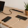Modern office desk with power outlets, laptop, and potted plant for productive workspace.