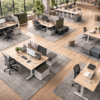 Ergonomic office desks with adjustable height and supportive chairs in a bright, open-plan workspace.