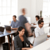 Office workspace with employees collaborating and working on laptops in a bright, modern environment.